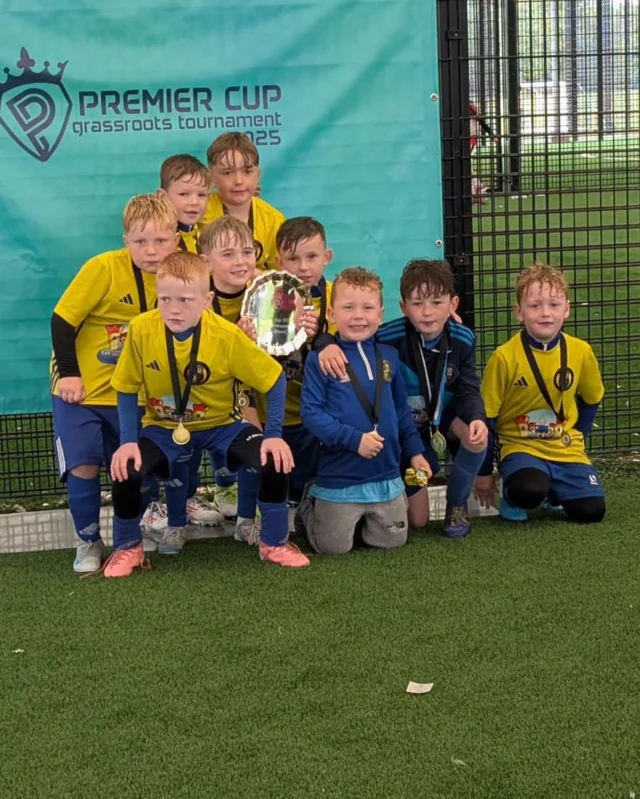 💙💛 2016s Champions 💛💙

Last week, our 2016s Blues participated in the Premier Cup for the second year in a row, after winning the shield last year.

During the group stage, the lads had some great games. They beat Celtic Bhoys 2-0 with goals from Francisco O’Brien and Cillian Dempster. They also beat Chimney Corner 1-0 thanks to a great goal from Young Cisco. Similar to last year, the lads finished 3rd out of 5 teams in their group and advanced to the shield competition.

Into the quarter-final, the wee Hill started playing some really lovely football. They breezed past Carnmoney Colts, winning 3-0 with goals from Cillian Dempster and Cisco O’Brien, who scored a brace.

The semi-final was a much tougher task against a strong Shankill Juniors side. After plenty of wasted chances from our lads, Shankill Juniors found themselves through one-on-one, only to be denied by a big save from goalkeeper Brooklyn Fryers. The game finished 0-0 and went to penalties. Brooklyn Fryers was the hero again, making a crucial penalty save to win the shootout.

In the final, the lads met Trojans, a side they’d never faced before. After a nervy start, the lads got going, and Cillian Dempster broke the deadlock with a tidy finish. The pressure was on as Trojans threw everything they had at us. Our defense held strong, and with just seconds to go, Francisco O’Brien got the ball and drove past 4 players to slot home the goal that sealed the shield.

For the second year in a row, our lads have come away with the shield at this tournament.

Player of the tournament: Brooklyn Fryers 🧤😎
Special Mention to Fionn McKeever, who got man of the match in the final 🔥

💙💛 Newhill 2016s Proudly Sponsored by TEAMS & Let Me Entertain You Party Events 💙💛